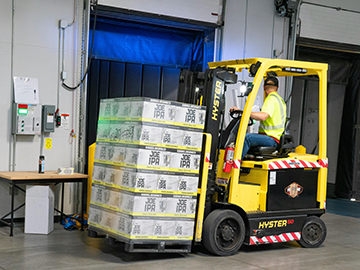 A warehouse worker forklifts incoming stock, organizing inventory management.