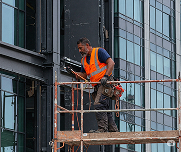 A maintenance technician inspects and repairs a commercial building’s exterior as part of a proactive building plan
