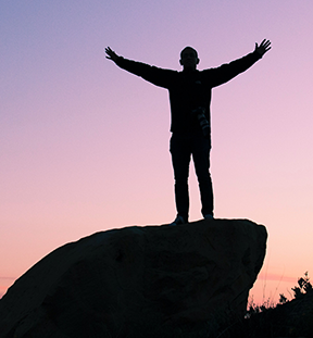 Image: man on rock arms wide