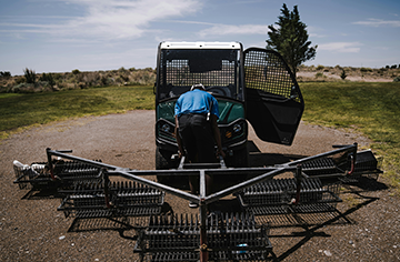 Groundskeeper maintaining sand traps as part of routine golf course maintenance.