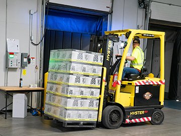 A warehouse worker forklifts incoming stock, organizing inventory management.
