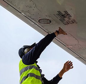Image: maintenance man looking at a plane's wing